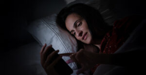digital detox ragazza a letto con cellulare acceso